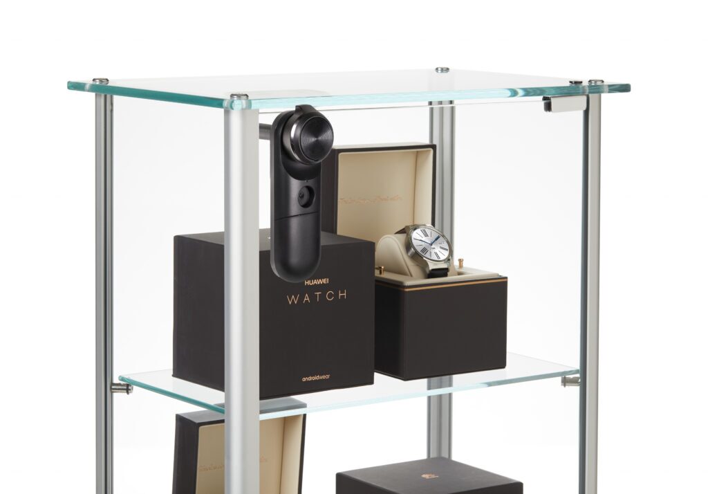 InVue LIVE Cam Lock instalado en una vitrina de cristal para sujetar los relojes inteligentes, empaquetados, que se exponen en las estanterías