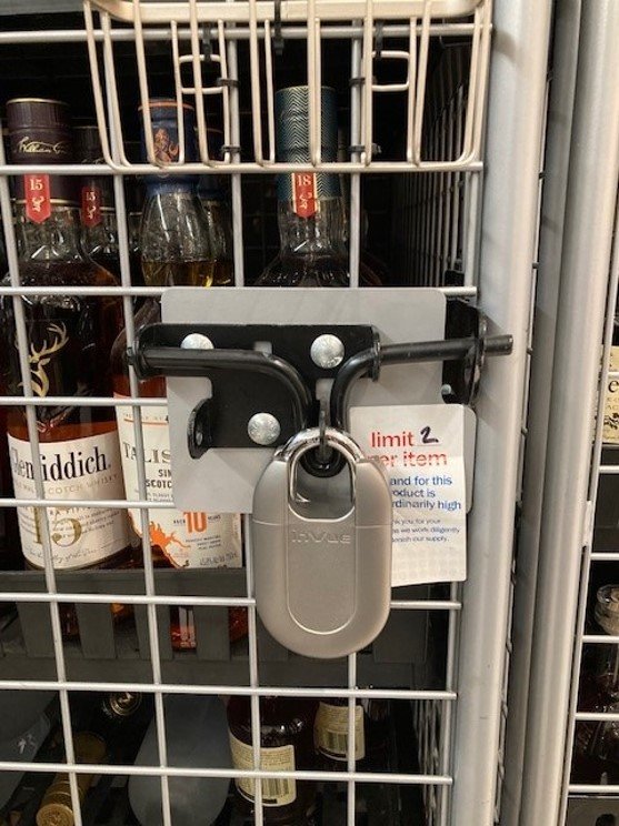 Padlock protegiendo botellas de licor en una jaula en una tienda Meijer