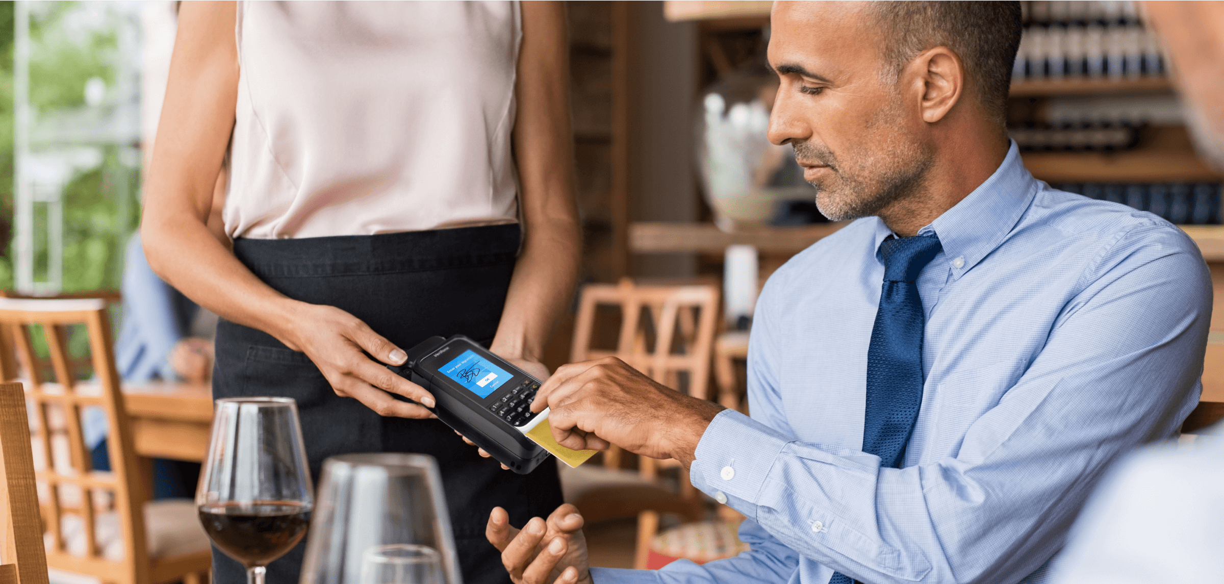 Hombre usando mPOS Handheld Case para completar el pago en un restaurante.