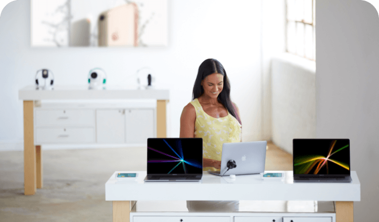 Mujer mirando portátiles sobre una mesa en una tienda de telefonía móvil