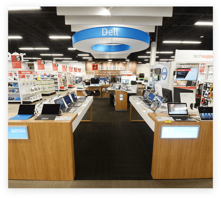 Ordenadores Dell en exposición segura sobre mesas en Office Depot