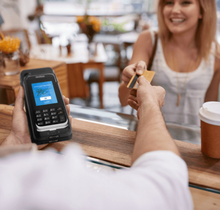 Mujer entregando una tarjeta de crédito a un trabajador que sostiene un mPOS