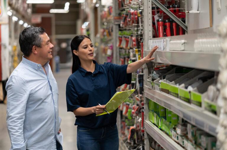 Hombre comprando en una tienda de bricolaje y hablando con una vendedora