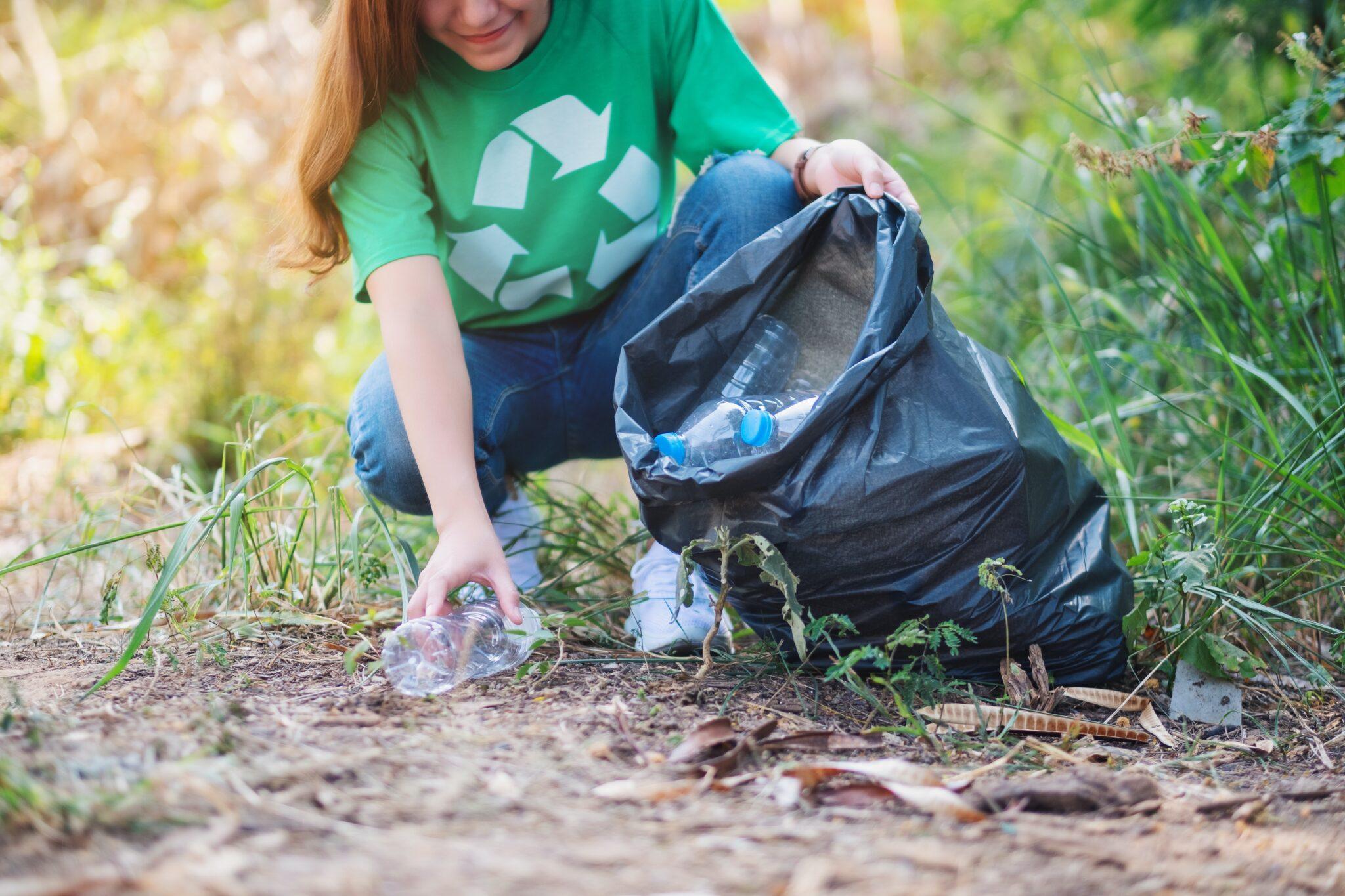 Mujer recogiendo reciclaje y tirándolo a la basura